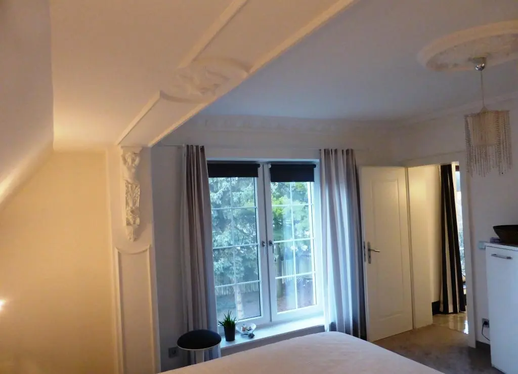 Helles Schlafzimmer mit großer Fensterfront und Stuckelementen
