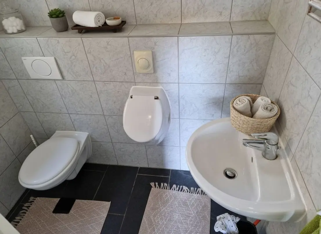 Gefliestes Gäste-WC mit Toilette, Bidet und Waschbecken