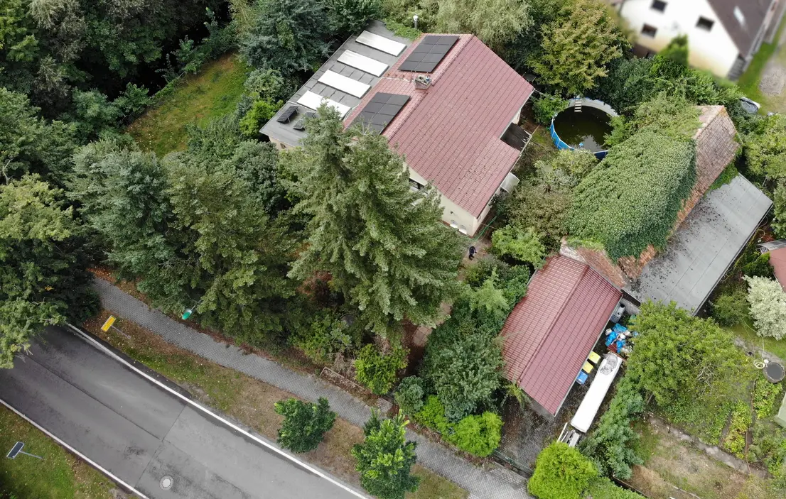 Luftaufnahme von Wohnhaus, großem Garten, Carport, Scheune und Straße