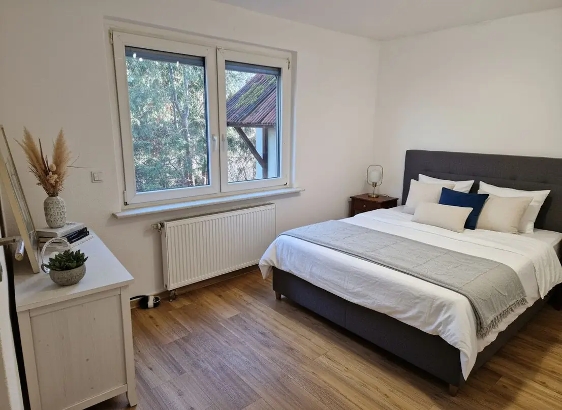 Helles Schlafzimmer mit Doppelbett und Fenster zum Garten