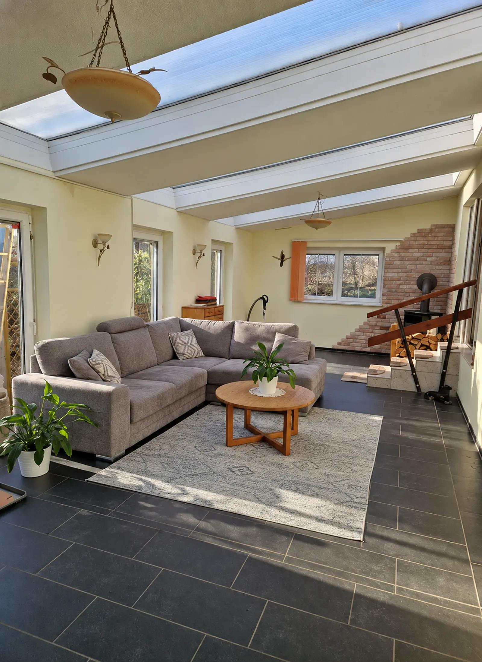 Heller Wintergarten mit Sitzbereich, Kamin und Zugang zum Esszimmer