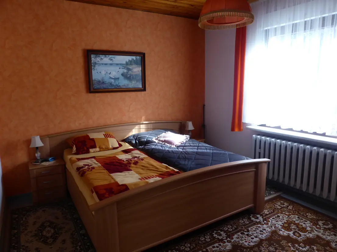 Schlafzimmer mit Doppelbett und Fenster zum Garten
