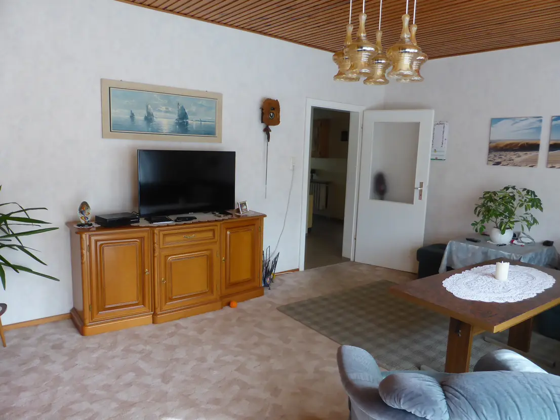 Wohnbereich mit Fernseher und großer Schrankwand