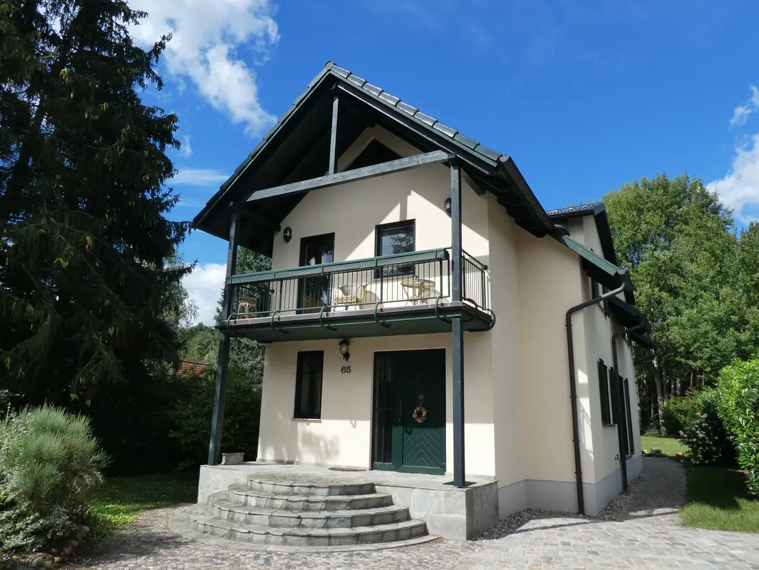 Nahe Vorderansicht des Hauses mit Balkon und geschwungener Eingangstreppe